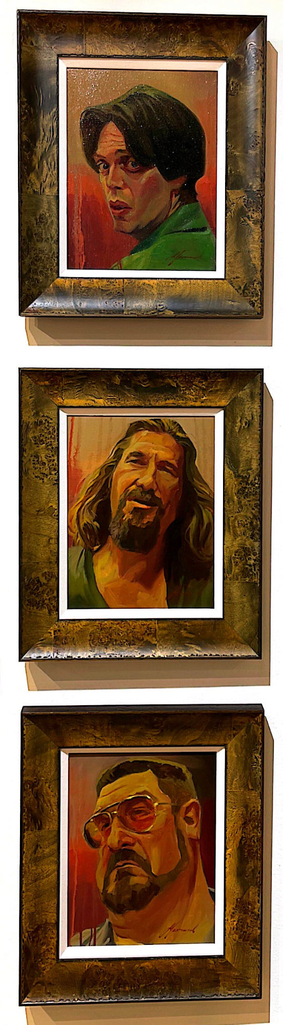 Gabe Leonard's paintings of Big Lebowski characters. One man is wearing a green shirt. One man has shoulder length hair and goatee. Third man is wearing orange tinted sunglasses with a short haircut and a beard.