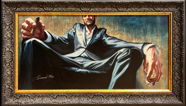 Gabe Leonard's art work of a man sitting in a deep arm chair holding a cigar in his right hand and a shot glass with amber colored liquid in his left hand. The art is also custom framed with a thin gold frame and a vintage inspired brown wood frame.